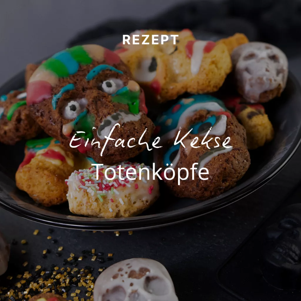 Ein Teller mit Halloween-Keksen in Form von Totenköpfen und Monstergesichtern, verziert mit buntem Zuckerguss und Streuseln. Der Text darüber lautet auf Deutsch: Rezept: Einfache Totenkopf-Kekse.